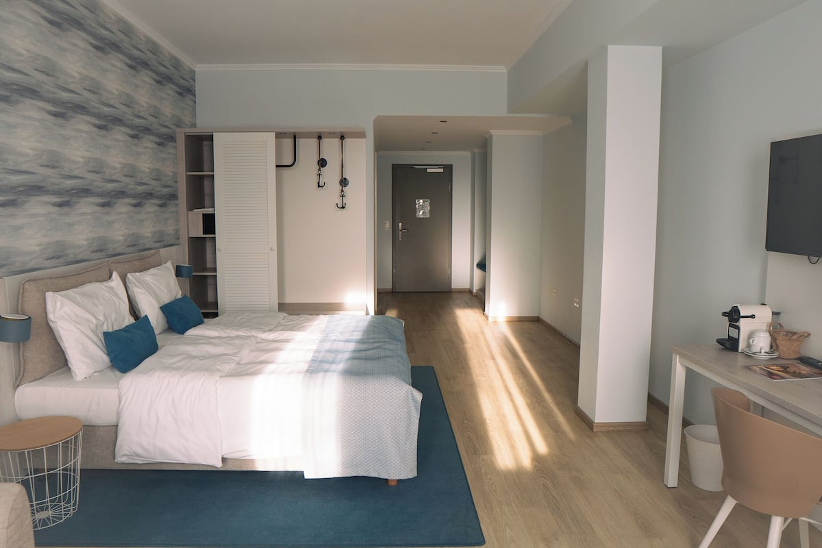 A modern hotel room with a large bed, a desk, and a television.
