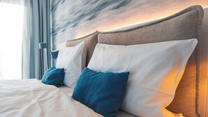 Una cama bien hecha con almohadas blancas y turquesas, un cabecero de madera y un diseño moderno.