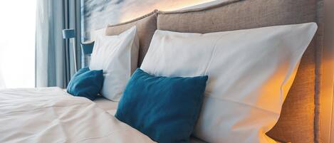 A neatly made bed with white and teal pillows, a wooden headboard, and a modern headboard design.