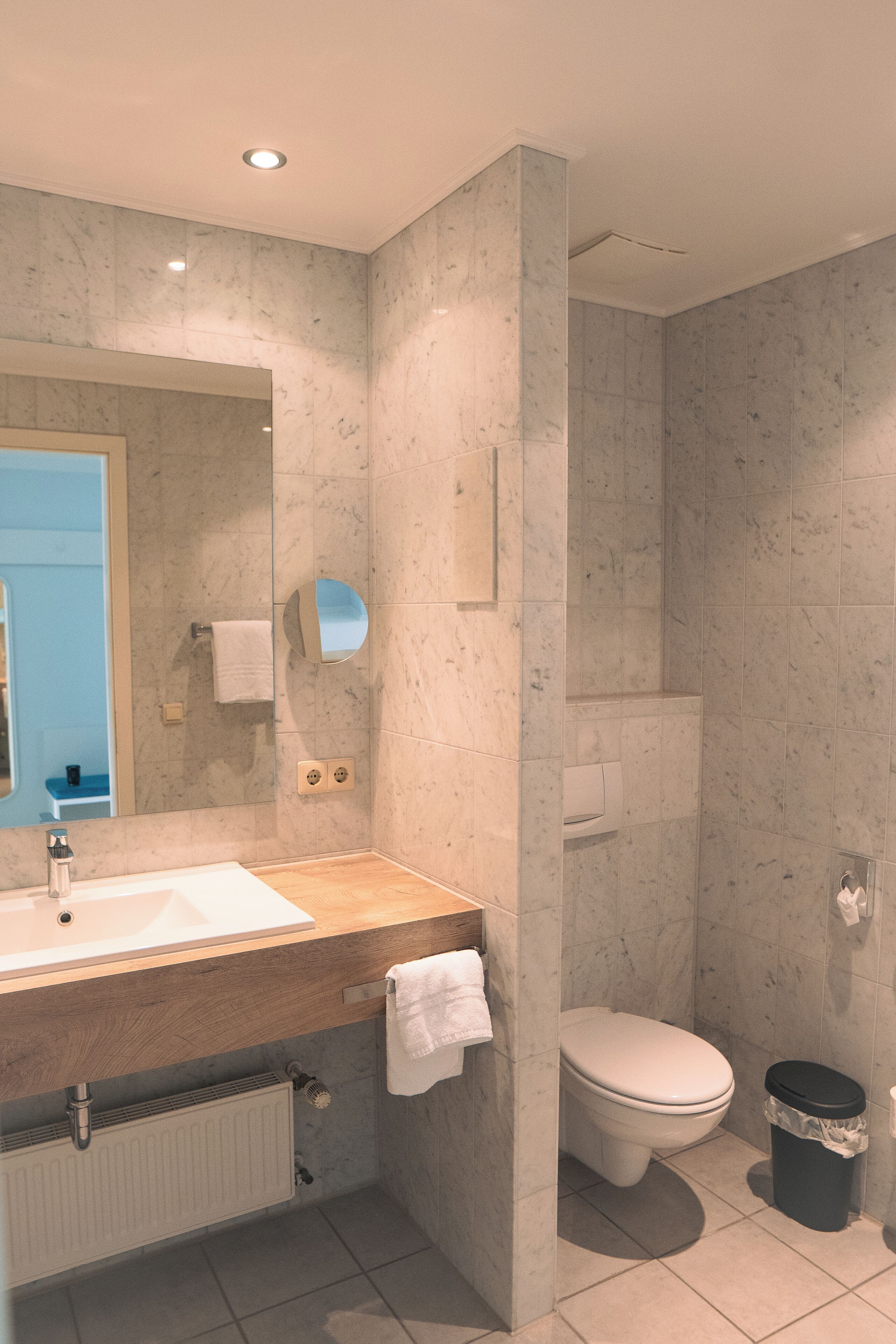 A modern bathroom with a marble sink, a toilet, and a shower area.