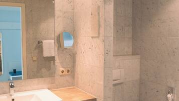 A modern bathroom with a marble sink, a toilet, and a shower area.