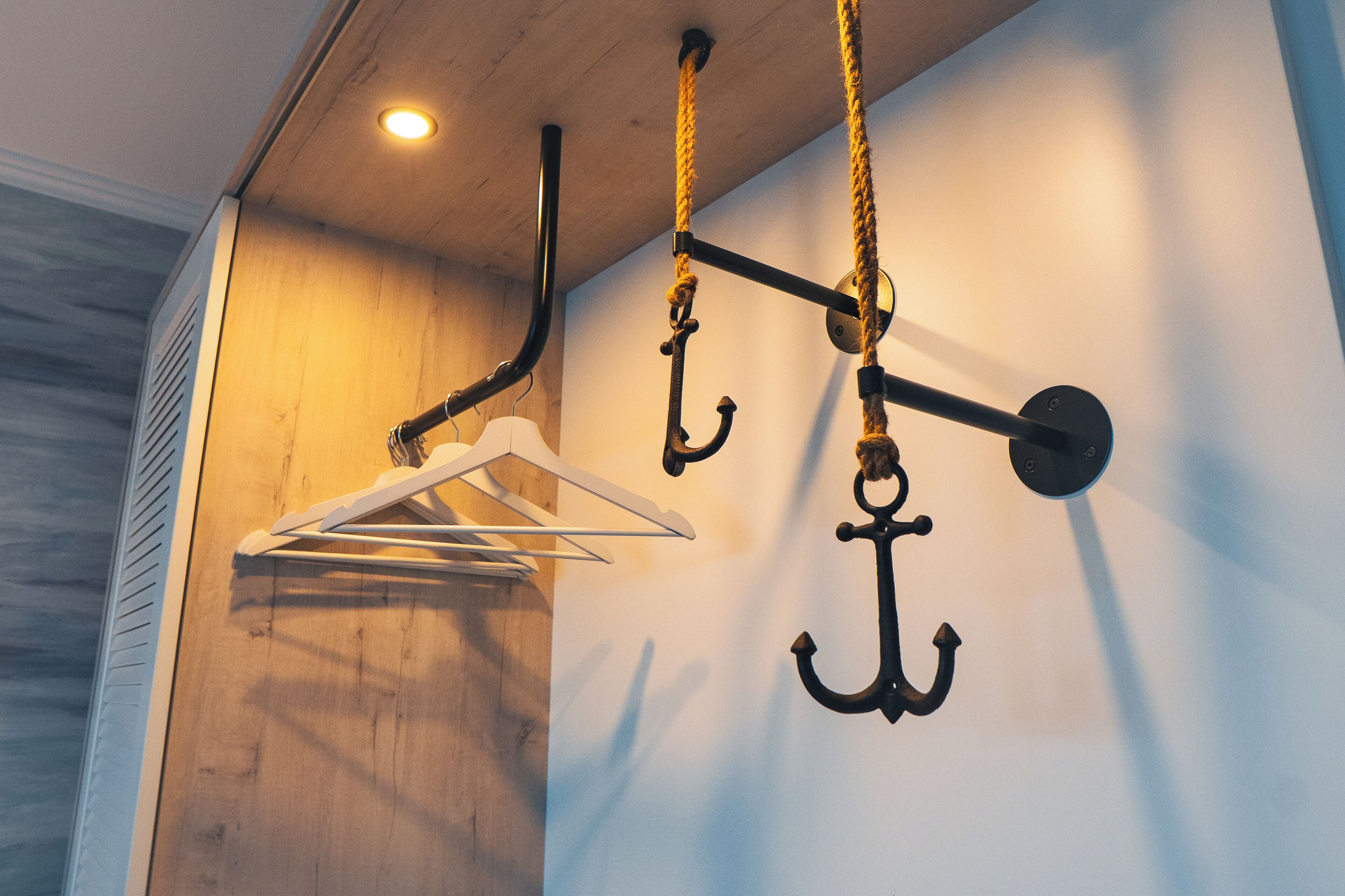 A wooden wall with a hanging rack and a black metal coat hook.