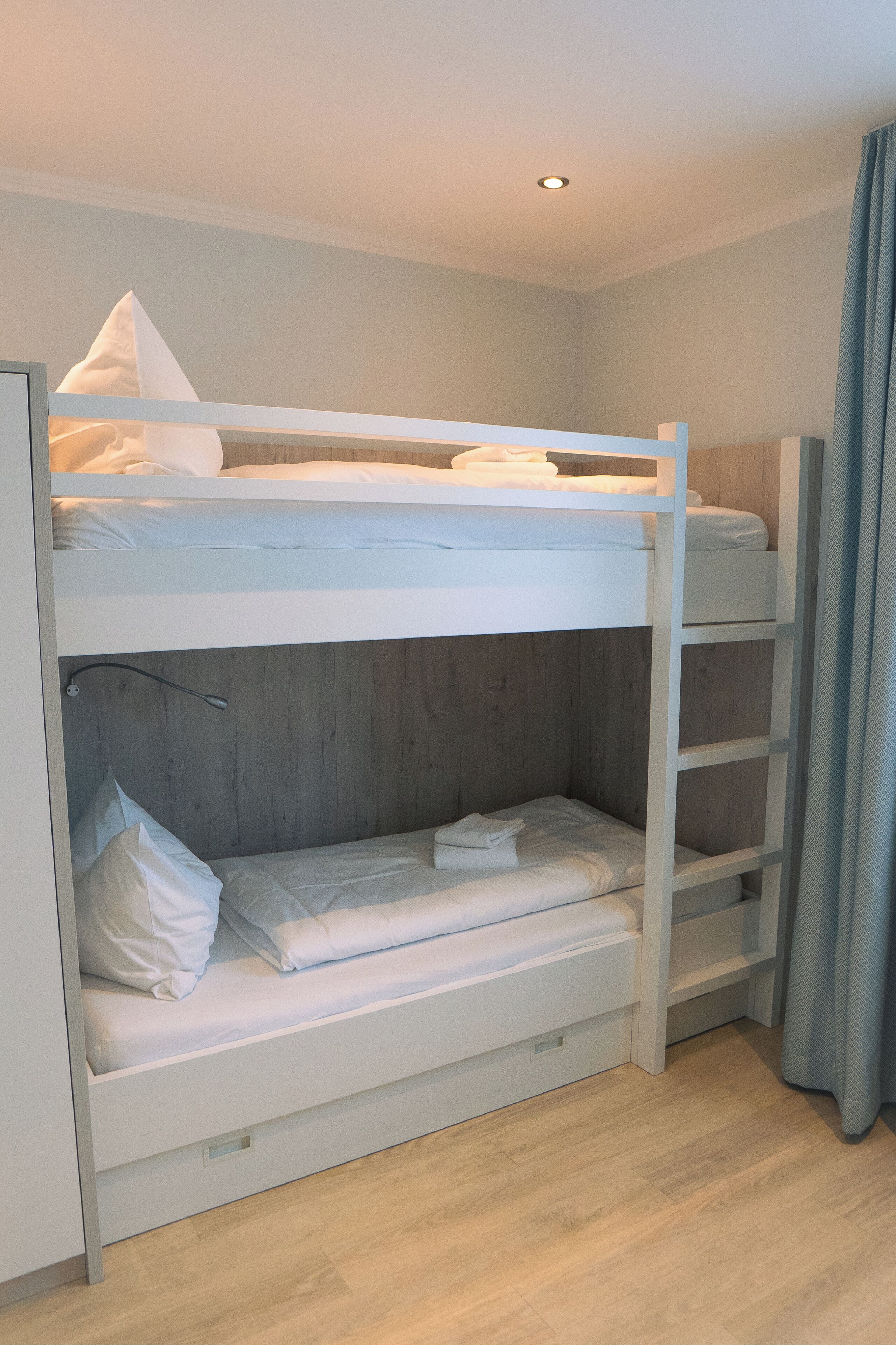 Una cama litera con ropa de cama blanca y un cabecero de madera.