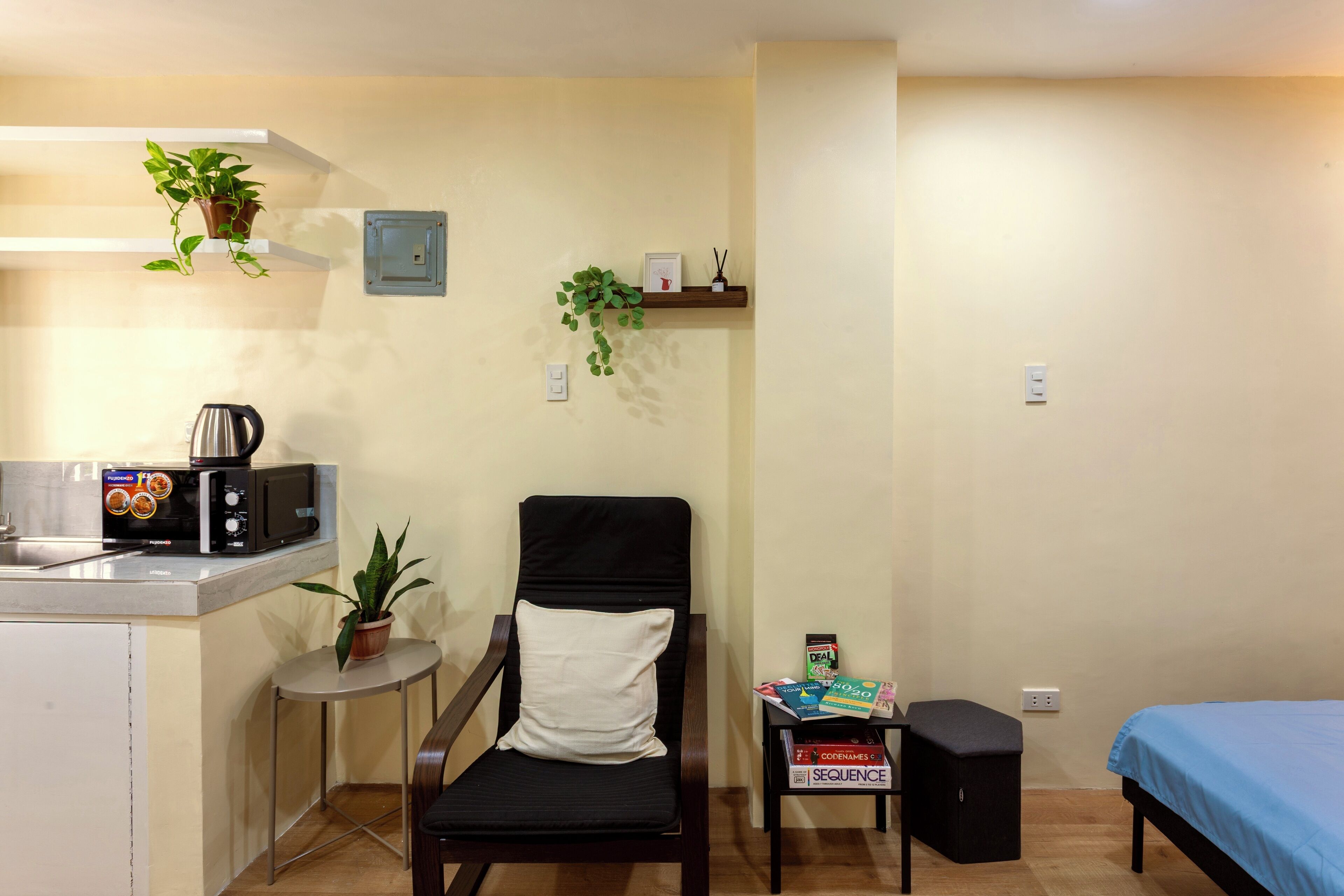 A compact living space with a kitchenette, a dining area, a bed, and a small table with a chair.