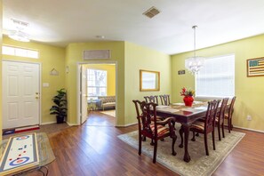 A dining area with a wooden table and chairs, a chandelier, and a potted plant. - Family Retreat | Walk to Lake | Pool Access (Garland)