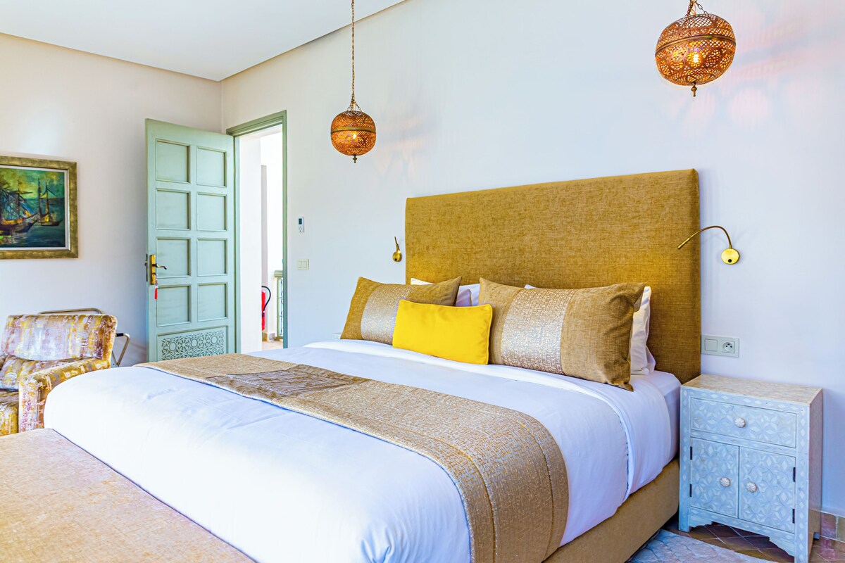 A bedroom with a bed, bedside tables, a chair, and a door.