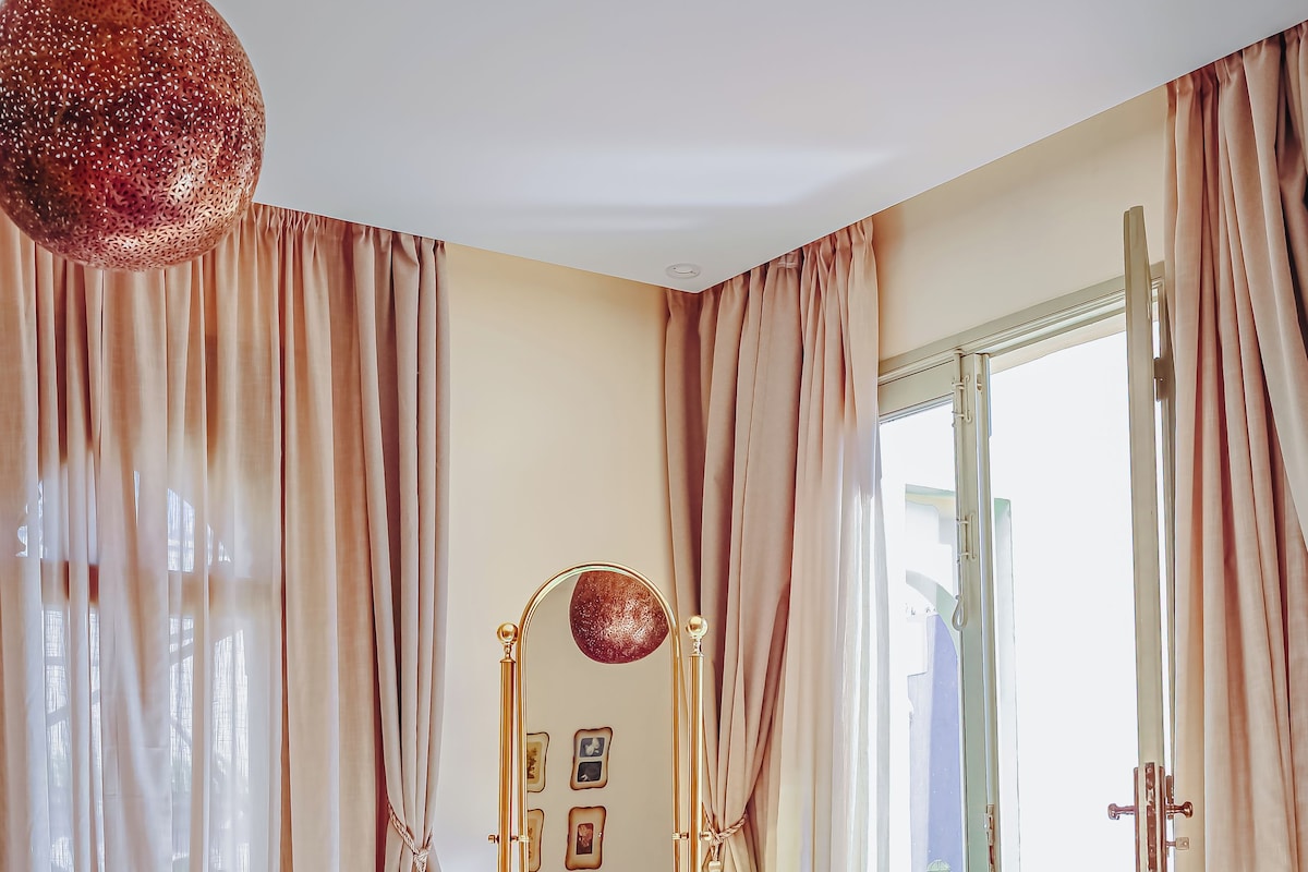 A bedroom with a bed, a dresser, a mirror, and a view of the outdoors.