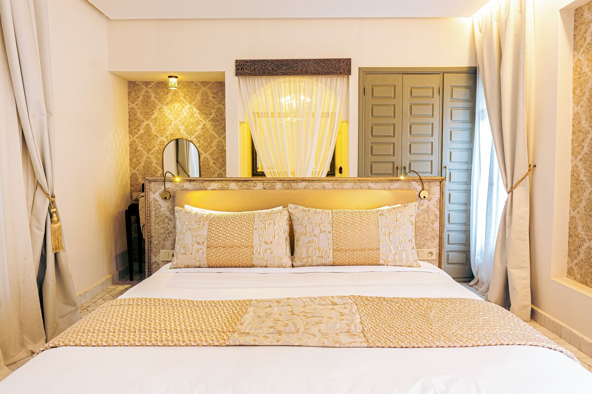 A hotel room with a bed, a mirror, a door, and a window with curtains.