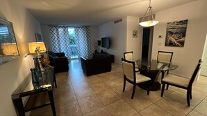 Ein modernes Wohnzimmer mit einem Glastisch, schwarzen Sofas und einem Fernseher.
