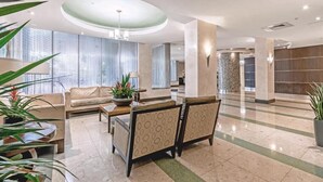 En rummelig lobby med sofa, stole, sofabord og potteplanter.