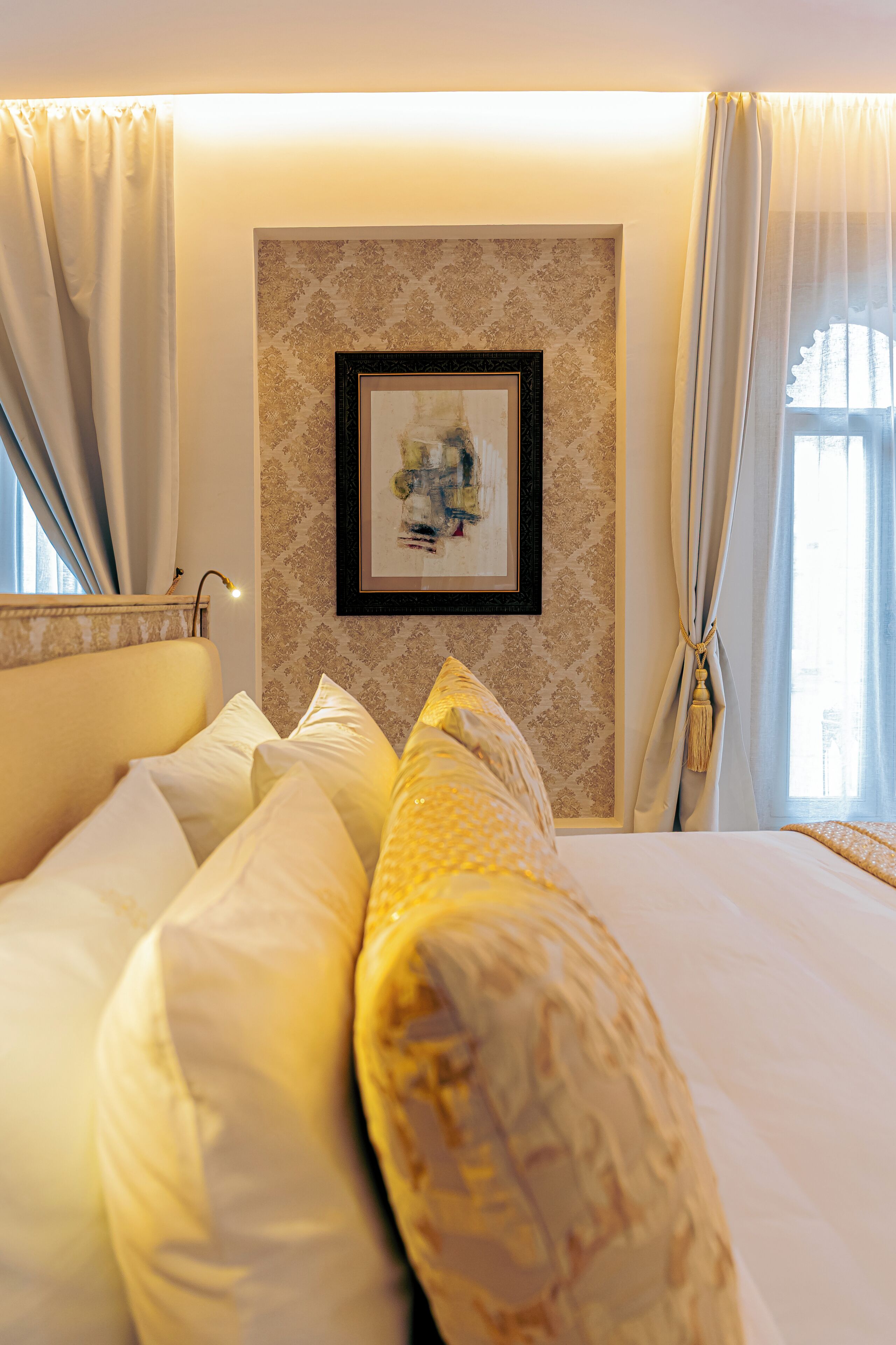 A hotel room with a bed, a framed artwork on the wall, and curtains.