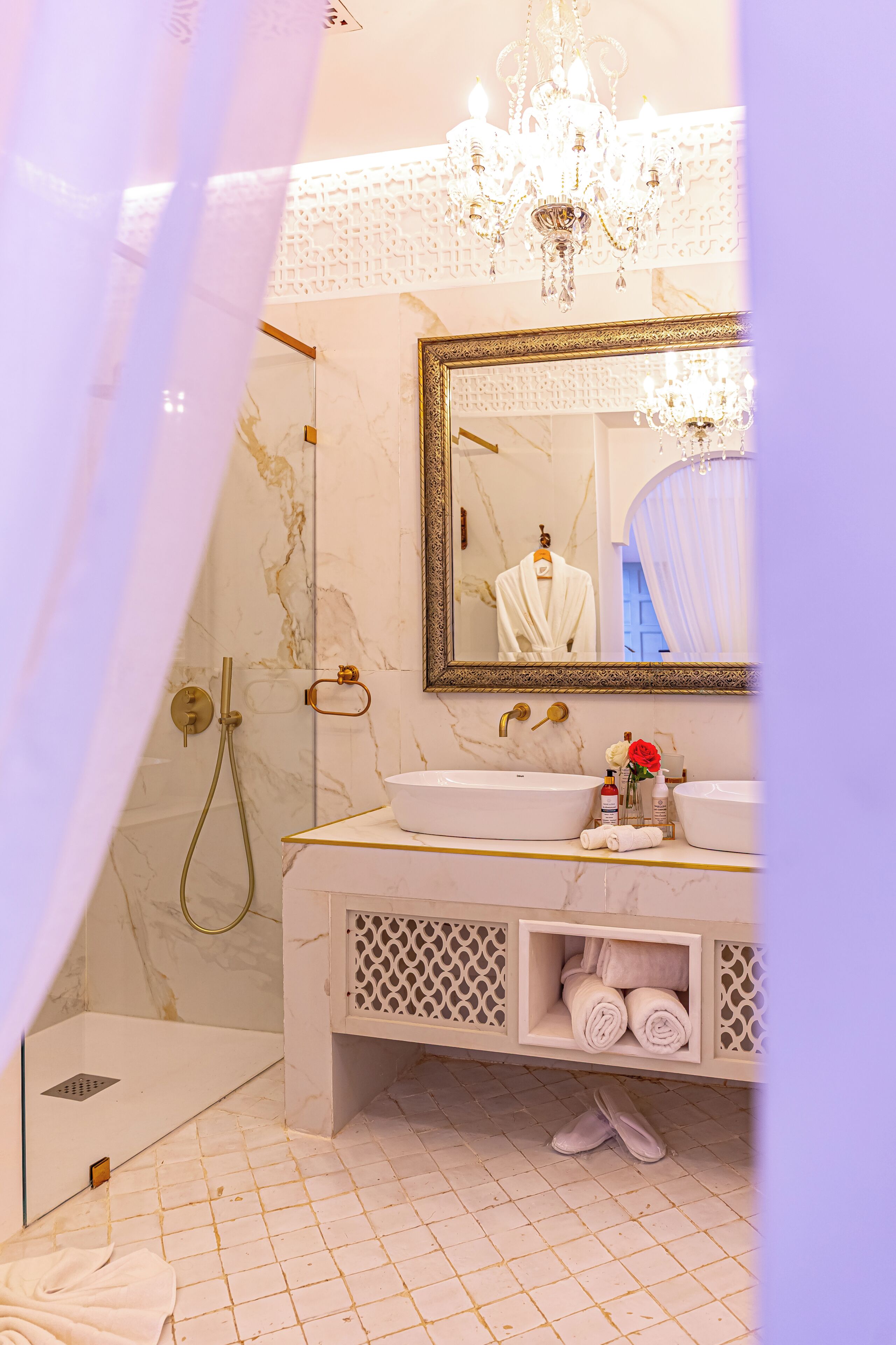 A bathroom with a large mirror, a chandelier, a bathtub, and a shower.