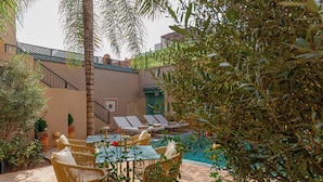 A poolside area with lounge chairs, a table, and a staircase leading to an upper level. - Kasbah La Moun The Art of Hospitality (Marrakech)