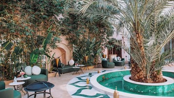 Un jardin intérieur doté d’une piscine, d’espaces aménagés pour s’asseoir et d’une grande variété de plantes.