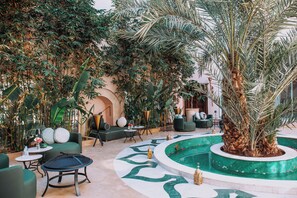 An indoor garden with a pool, seating areas, and a variety of plants. - Kasbah La Moun The Art of Hospitality (Marrakech)