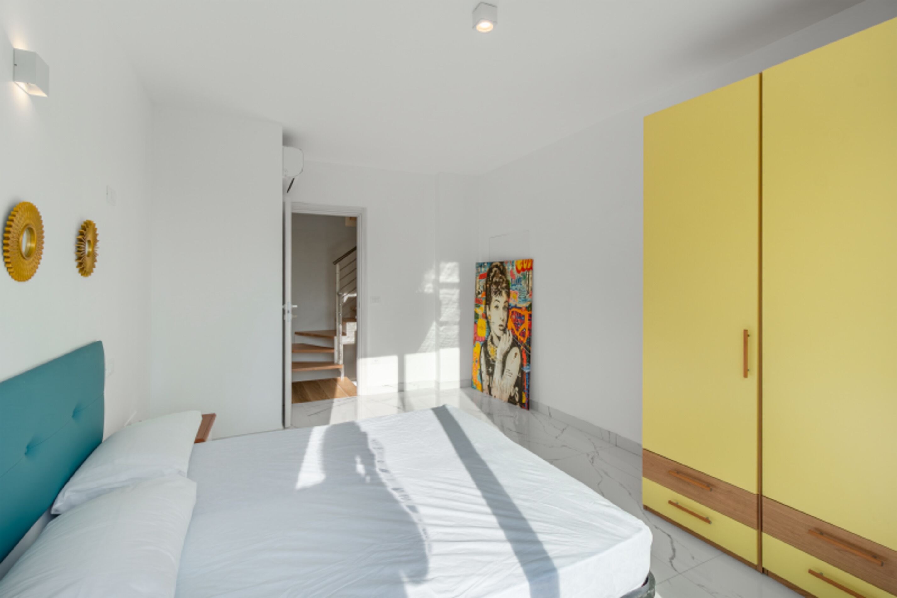 Een slaapkamer met een bed, een kledingkast en een schilderij aan de muur.