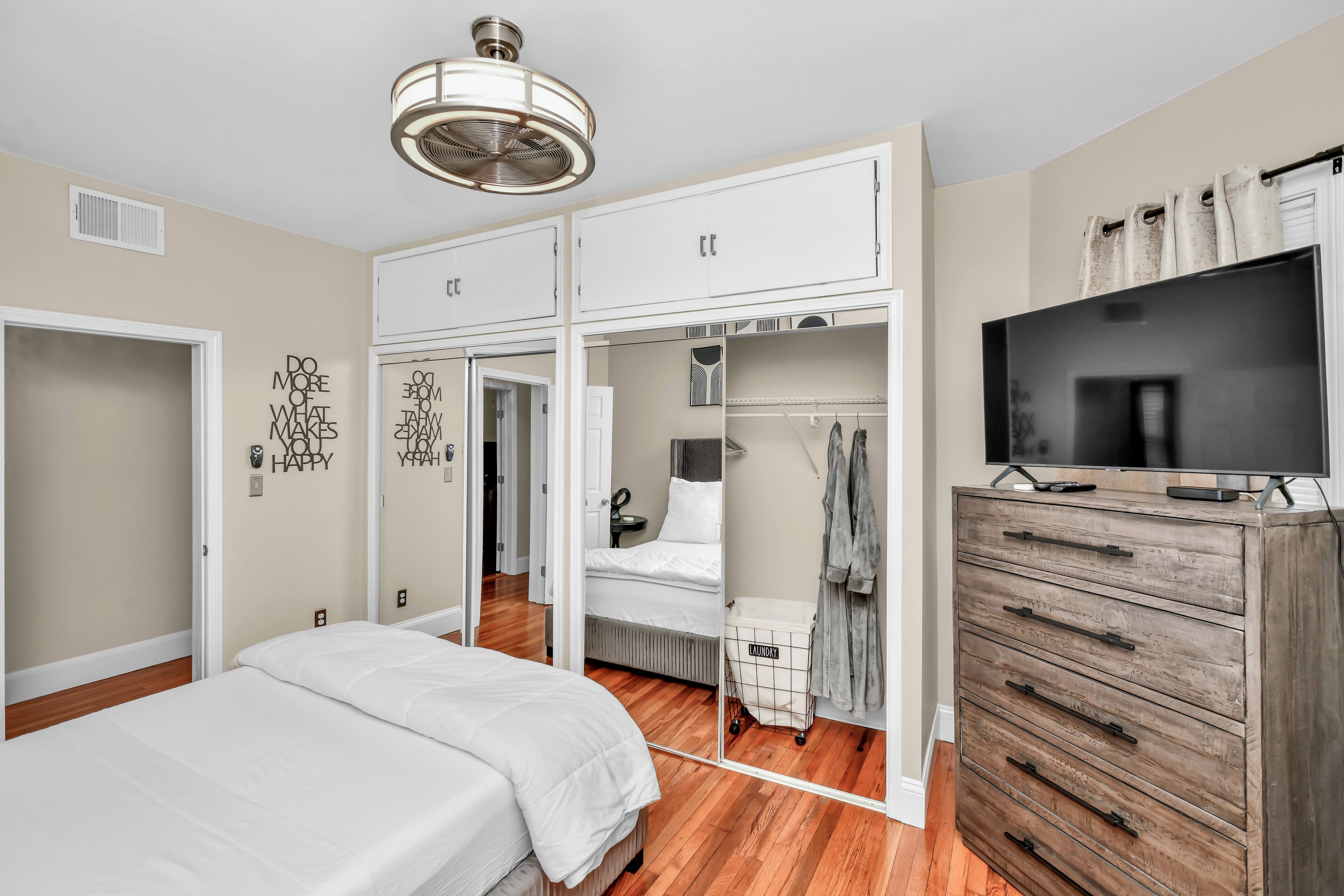 Ein Schlafzimmer mit Bett, Kleiderschrank und Fernseher auf einer Kommode.
