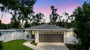 Ein modernes, zweistöckiges Haus mit Garage, umgeben von einem weißen Zaun und einem gepflegten Rasen.