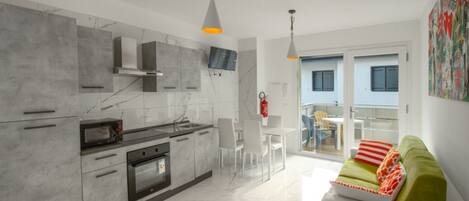 A modern kitchen with marble countertops, a built-in oven, and a dining area with a white table and chairs.
