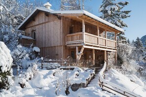 Une cabane en bois dotée d’un balcon, entourée d’arbres couverts de neige.