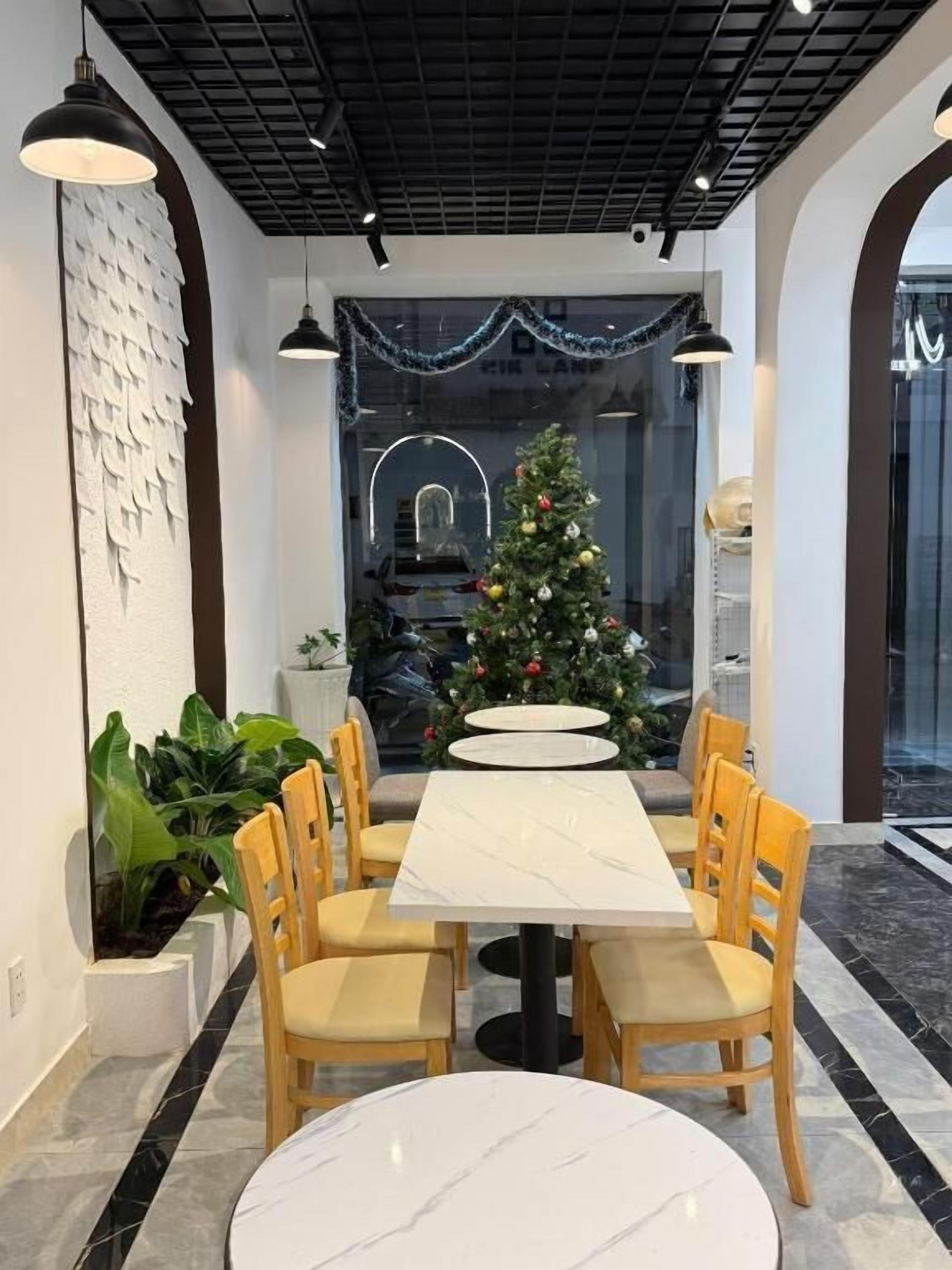 A modern dining area with a marble table, wooden chairs, a Christmas tree, and a decorative wall.