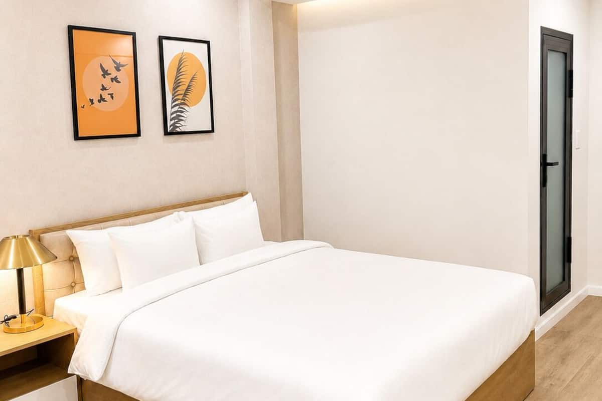 A modern bedroom with a wooden bed, a nightstand, a lamp, and two framed artworks on the wall.