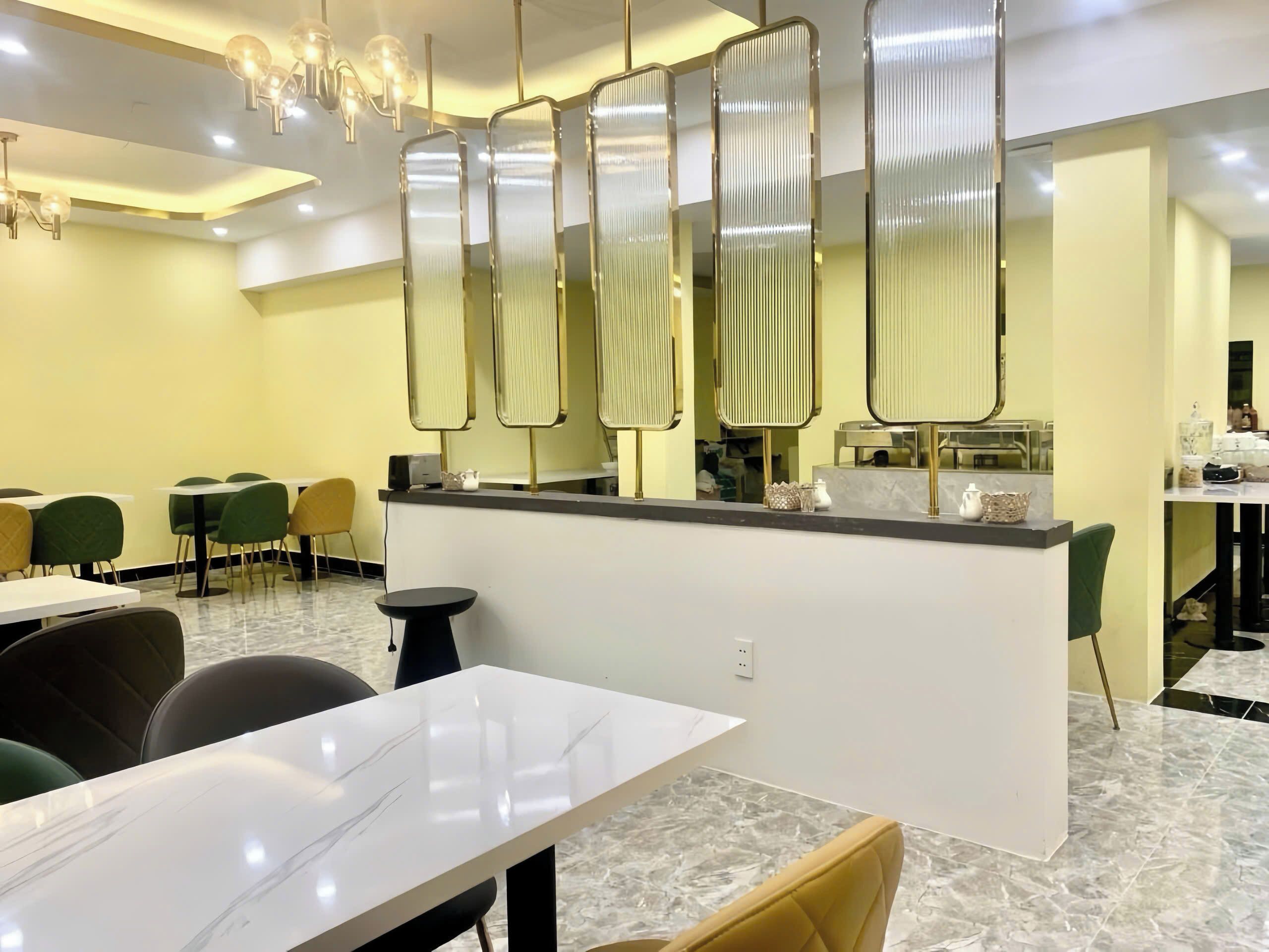Un moderno vestíbulo de hotel con piso de mármol, una recepción y un área de estar con mesas y sillas.
