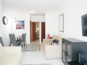 Ein modernes Wohnzimmer mit einer Couch, einem Esstisch mit Stühlen, einem Fernseher und einem Kamin.