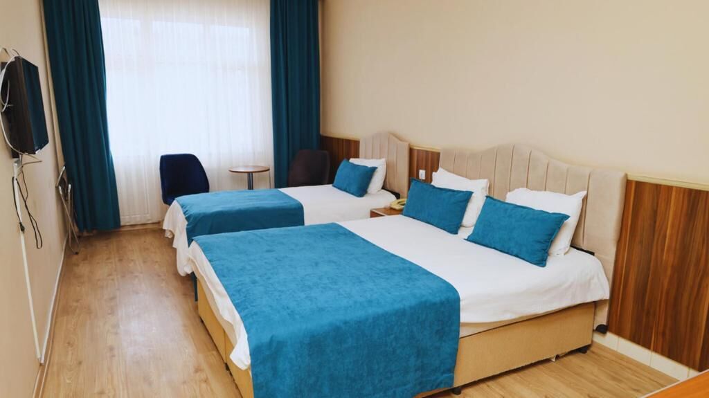 A hotel room with two beds, a TV, a chair, and a small table.