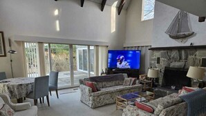 Amplia sala de estar con chimenea, televisor y comedor con mesa y sillas.