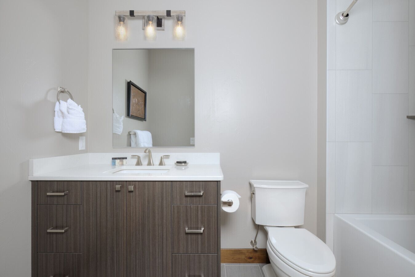 A modern bathroom with a white vanity, a toilet, and a shower area.