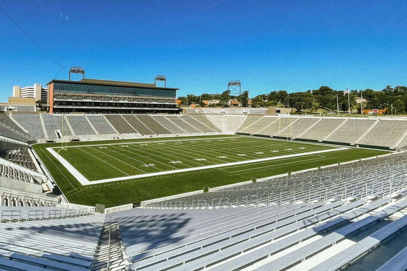A large, empty stadium with tiered seating and a football field.