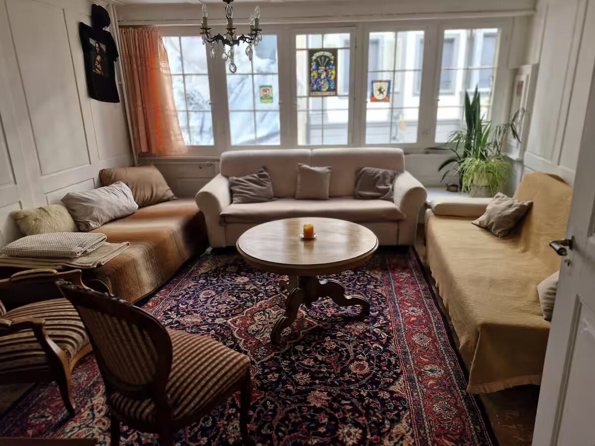 A cozy living room with a sofa, armchairs, a coffee table, and a patterned rug.