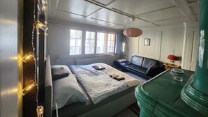 Ett rum med en säng, en soffa, ett bord och en grön pelare.
