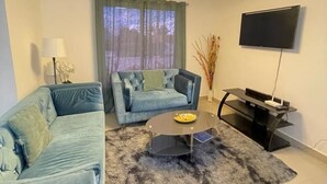 Een woonkamer met een bank, een salontafel, een televisie en een kroonluchter.