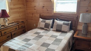 A cozy wooden room with a bed, dresser, and nightstand.