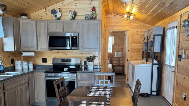 A cozy cabin-style kitchen with wooden cabinets, a central island, and a dining area with a checkered tablecloth.