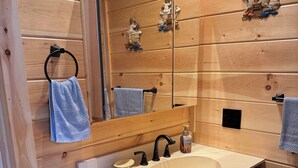 A wooden-paneled bathroom with a large mirror, a sink, and a towel rack.