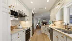 A modern kitchen with white cabinetry, stainless steel appliances, and a wooden floor. - Luxury Coastal Retreat | Salt Water Heated Pool (Sanibel)