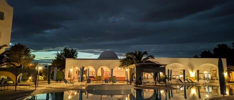Una piscina cubierta, una piscina al aire libre, sombrillas, tumbonas