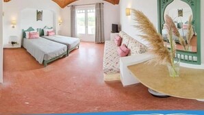Ein Zimmer mit zwei Betten, einem Schlafsofa, einem Spiegel und einer Zierpflanze.