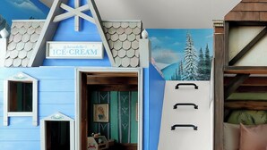 Een kamer met een blauwe muur, een bed met een wit hoofdeinde, een houten trap en een bordje met de tekst 'Ice Cream'.