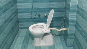 A small bathroom with a toilet, a shower, and a sink. - Kusum guest House  (Ayodhya)