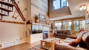A spacious living room with a fireplace, leather sofa, and a large TV. - Beautiful Breck Condo, block from Main and Gondola (Breckenridge)