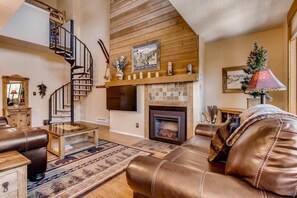 A cozy living room with a fireplace, leather sofa, and a wooden staircase. - Beautiful Breck Condo, block from Main and Gondola (Breckenridge)