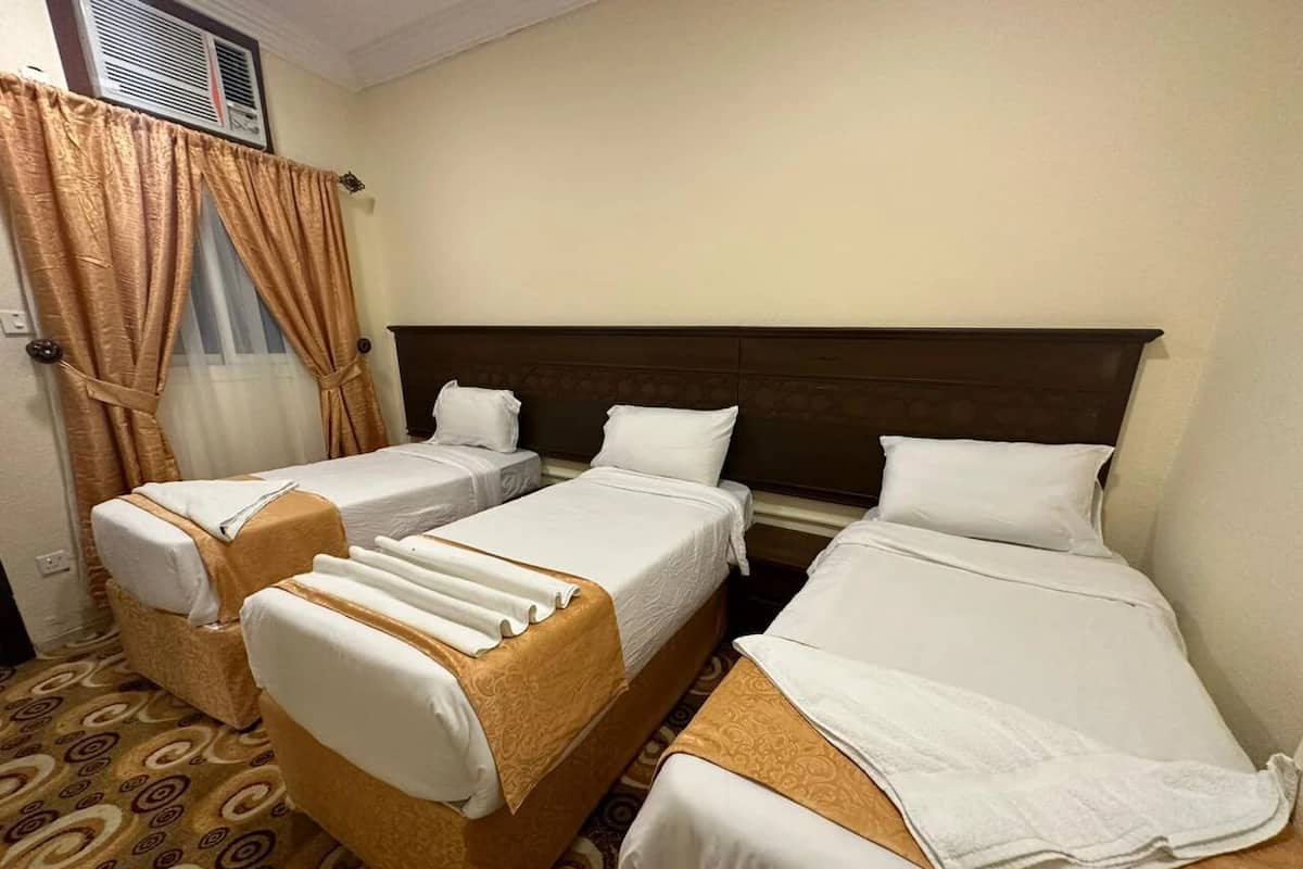Ein Hotelzimmer mit drei Einzelbetten, einem großen Bett und einer Schlafcouch.