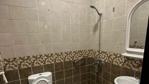 Et lille badeværelse med toilet, bruser og håndvask.