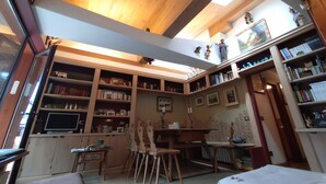 Ein gemütliches Zimmer mit Holzbalkendecke, einem Bücherregal, einem Schreibtisch und einem Stuhl.