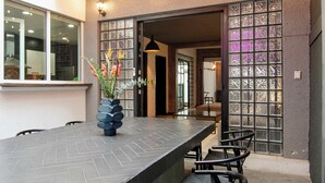 An outdoor dining area with a long table and chairs, a vase with flowers, and string lights above. - La Chula · Stylish Home in Condesa + Rooftop Bar (Mexico City)