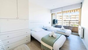 Une chambre d’hôtel moderne avec deux lits, une grande armoire et une vue sur la ville grâce à de grandes fenêtres.